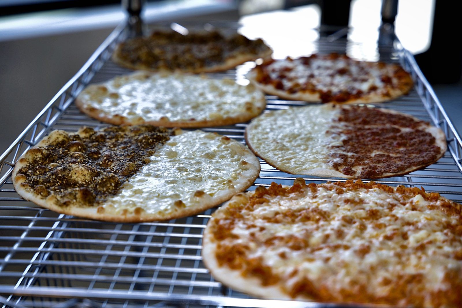 A rack of freshly baked Lebanese manakish cooling at Sahtein Bakery