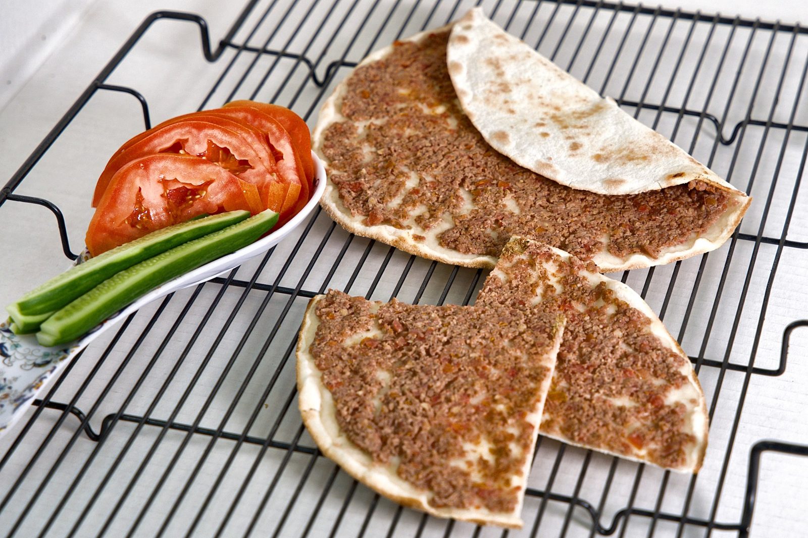 Lahm baajin sliced and served with fresh tomato and cucumber