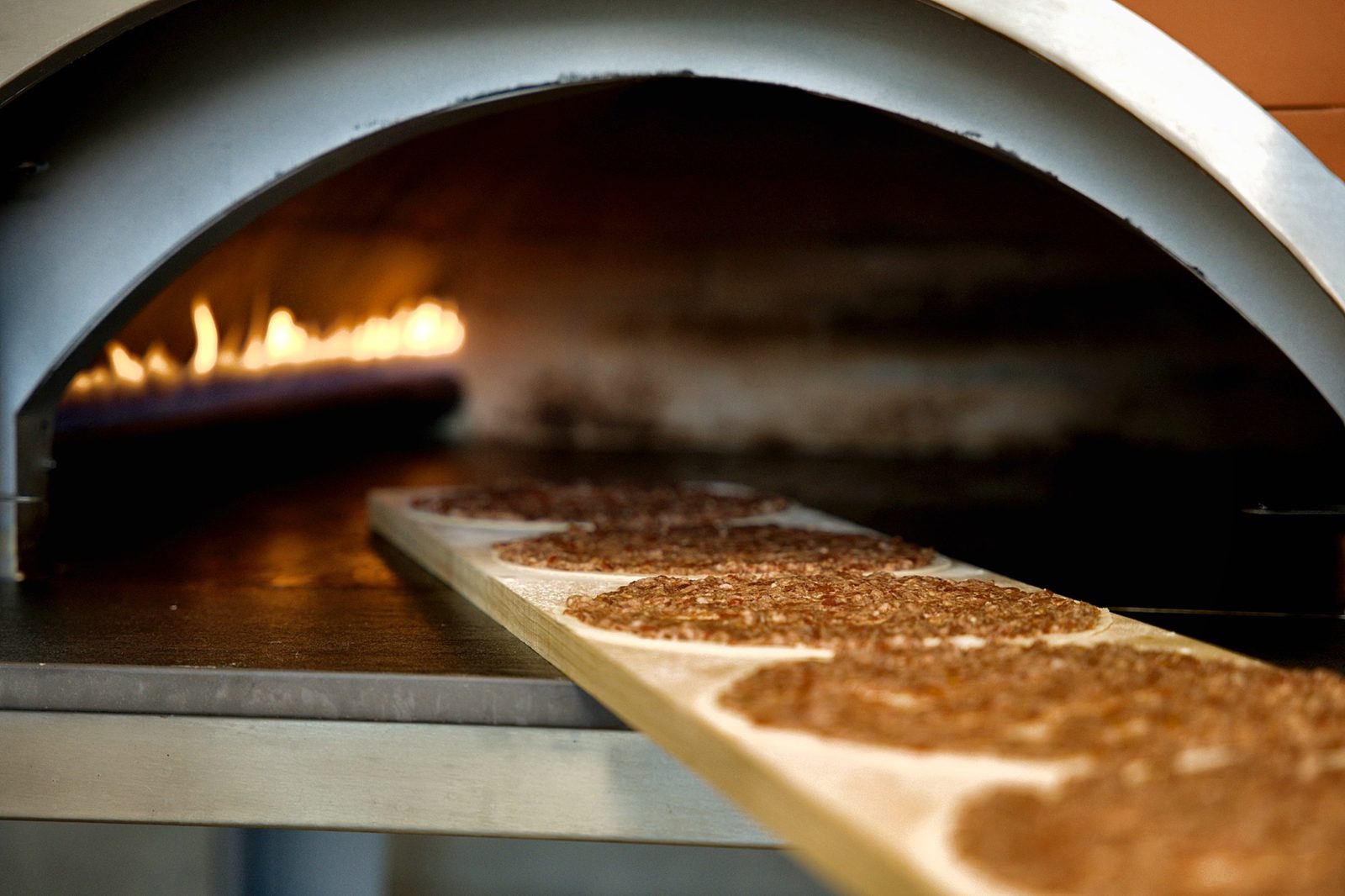 Fresh manakish going into the flame-fired stone oven at Sahtein Bakery